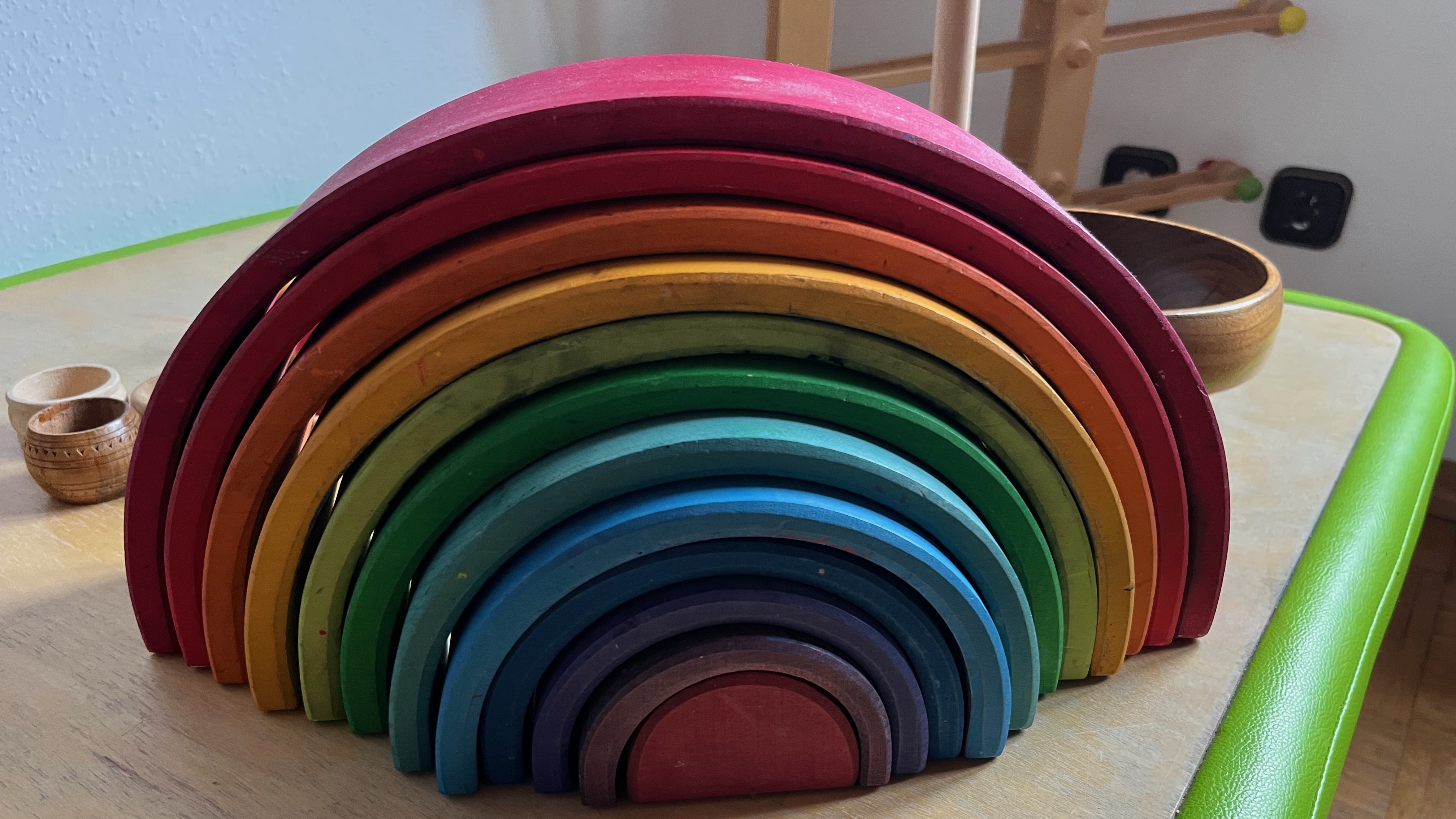 verschiedene bunte Halbkreise aus Holz, die zusammengestellt einen Regenbogen ergeben